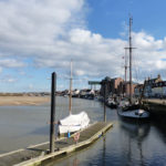 The pontoons for visiting boats stretch out into the channel towards the Albatros - a schooner now used as a restaurant and music venue moored on the Quay, Wells-next-the-Sea, North Norfolk. The iconic loading gantry of the former granary is in the background.
