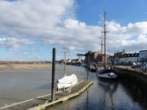 The pontoons for visiting boats stretch out into the channel towards the Albatros - a schooner now used as a restaurant and music venue moored on the Quay, Wells-next-the-Sea, North Norfolk. The iconic loading gantry of the former granary is in the background.