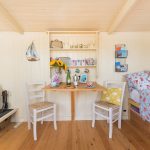 Dining table, wood burner and bed at the self-catering shepherd's hut, popular holiday accommodation for romantic breaks in Wells-next-the-Sea