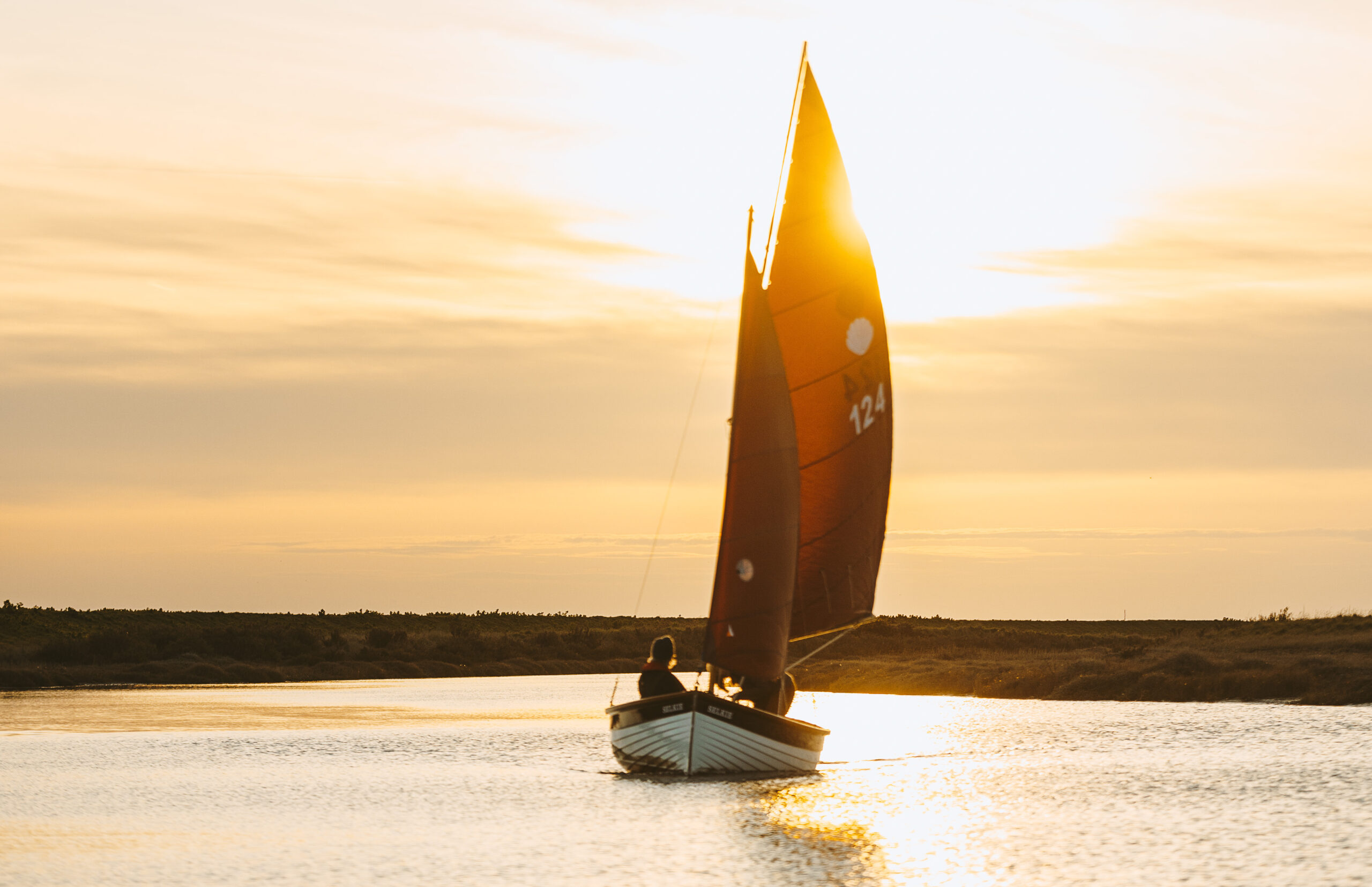 Sailing boat on a Sail North Norfolk charter at sunset in the saltmarsh